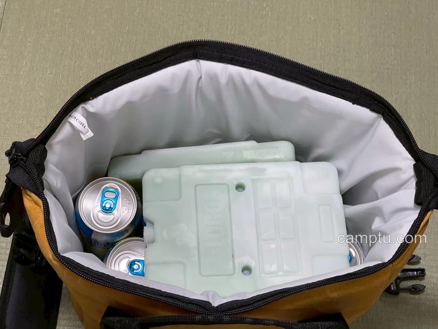 500ml缶と保冷剤2枚を入れた状態。これでもファスナーを閉めることができました。